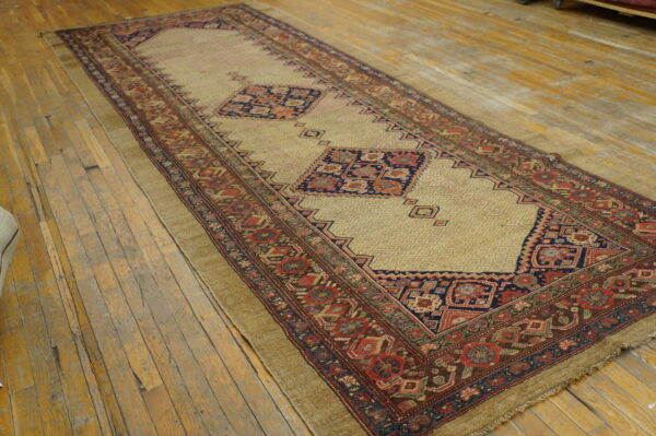 Low pile runner with a beige field, bold blue and red geometric medallions, resting on weathered wood.