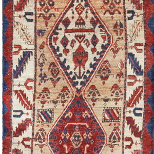 Narrow low-pile runner rug in tan, red, and blue featuring repeating centralized geometric diamond patterns.
