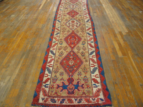 Red, blue, and beige geometric runner on a distressed wood plank floor.