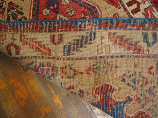 Low-pile geometric rugs in tan, red, and blue overlap on distressed wood plank flooring.