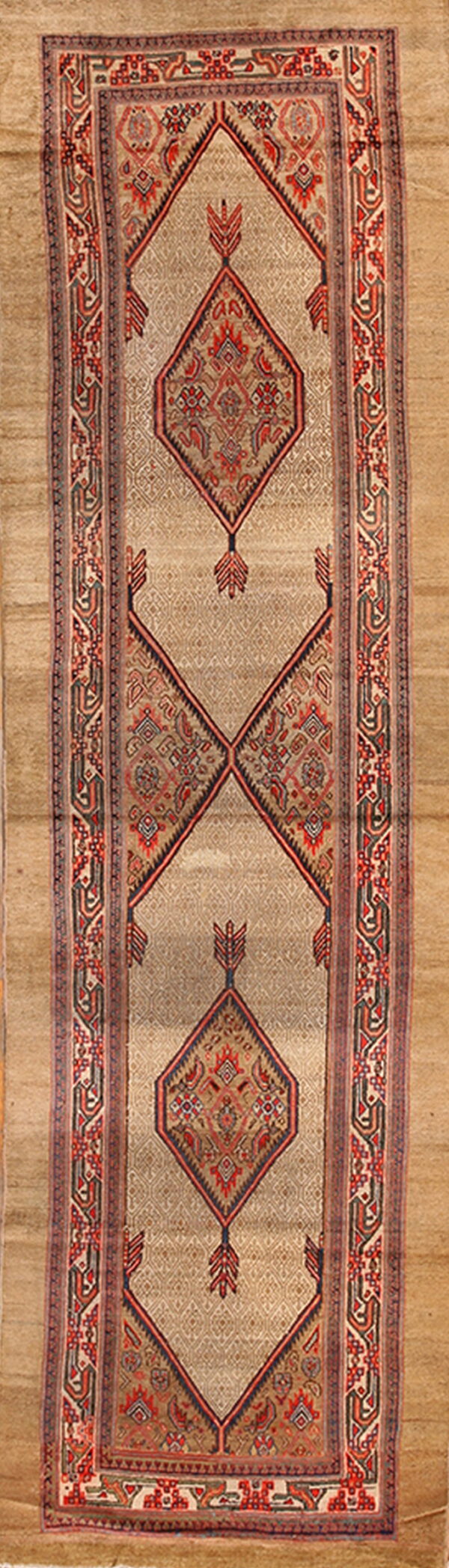 Tan runner rug with geometric diamond medallions, a repeating all-over pattern, and multi-layered red borders.