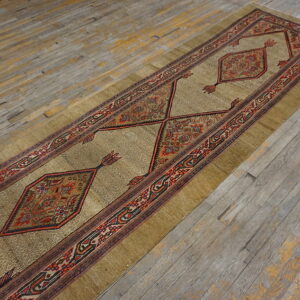 Earth-toned runner rug with red geometric guls and borders rests on rustic, worn wood planks.