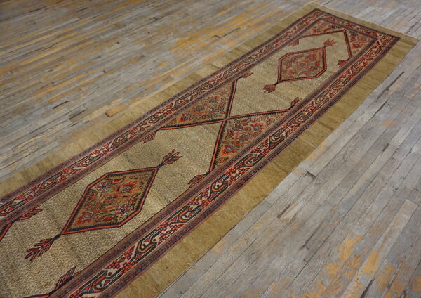 Earth-toned runner rug with red geometric guls and borders rests on rustic, worn wood planks.