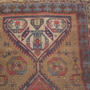 Low pile geometric rug featuring a large medallion motif in faded blue, red, and earthy brown.