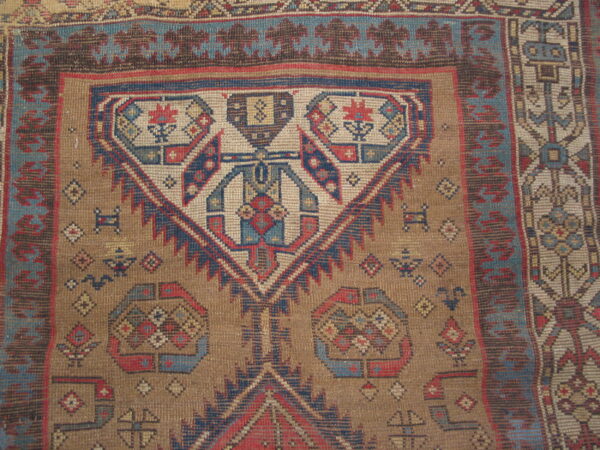Low pile geometric rug featuring a large medallion motif in faded blue, red, and earthy brown.