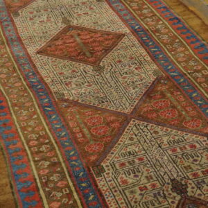 Low-pile runner rug with red, blue, and tan geometric patterns displayed on wooden plank floors.