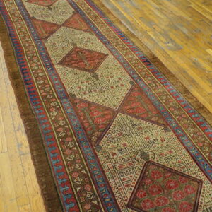 Muted earth tone runner with repeating geometric medallions sits on golden wood plank flooring.