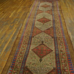 Geometric runner rug with repeating red and tan diamonds centered on distressed wood flooring.