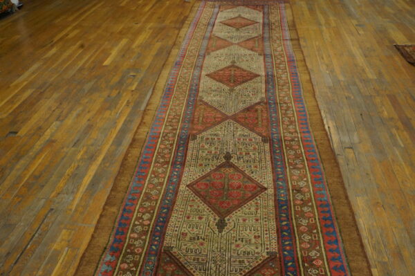 Geometric runner rug with repeating red and tan diamonds centered on distressed wood flooring.