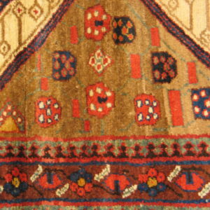 A textured, high-pile rug displays a tribal geometric design in camel, brown, red, and blue.