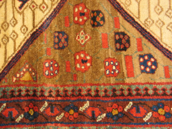 A textured, high-pile rug displays a tribal geometric design in camel, brown, red, and blue.