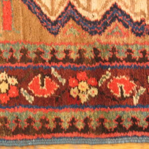 Detailed view of a high-pile rug with geometric and floral borders in rich reds, browns, and dark blues.