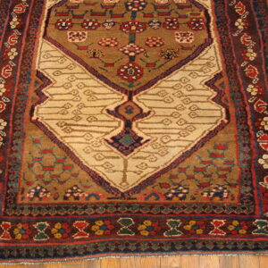 Brown and red rug with a prominent beige geometric motif rests on light wooden floorboards.