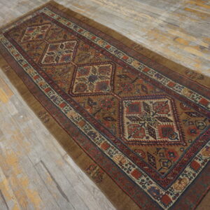 Brown runner rug with repeating geometric patterns in red and blue on weathered wood floors.