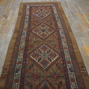 Geometric runner rug in browns, reds, and navy with large diamond motifs rests on worn wooden floorboards.