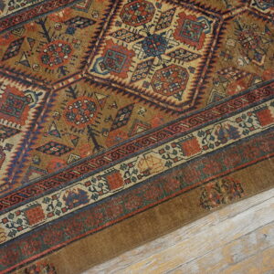 A detailed view of a brown, red, and blue geometric patterned rug lying on light wood flooring.