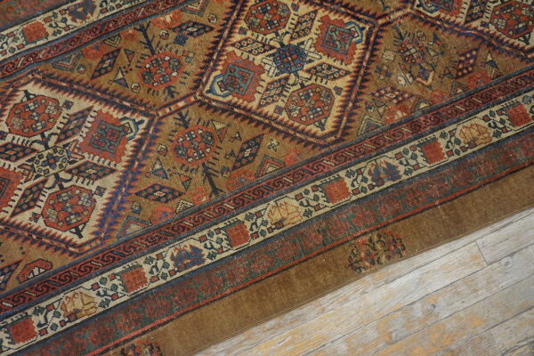 A detailed view of a brown, red, and blue geometric patterned rug lying on light wood flooring.