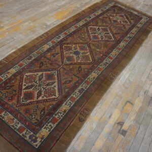 Brown and rust geometric runner rug displayed lengthwise on heavily distressed gray and yellow wood planks.