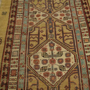 Low-pile runner with geometric medallions and multiple borders in gold, red, blue, and teal on wood planks.