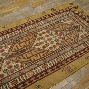 Geometric tan rug with red and teal accents on distressed gray wood flooring.