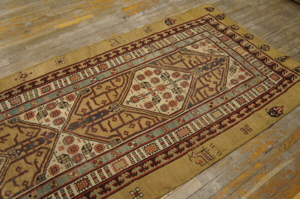 Geometric tan rug with red and teal accents on distressed gray wood flooring.