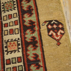A rug with colorful striped tribal borders in red, blue, and green rests on light brown distressed wood flooring.