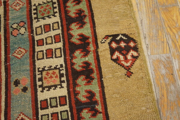A rug with colorful striped tribal borders in red, blue, and green rests on light brown distressed wood flooring.