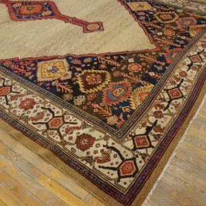 Intricate low-pile rug with a beige field and dark geometric border rests on aged hardwood planks.