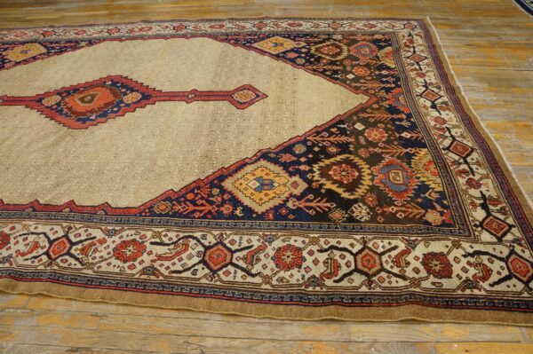 A beige field rug with geometric red, navy, and yellow patterns rests on rustic wood flooring.