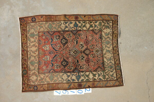 Traditional patterned rug with red, blue, and green geometric details lying flat on light gray concrete.