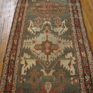 Muted geometric runner in sage green and rust orange covers a rustic wooden floor.