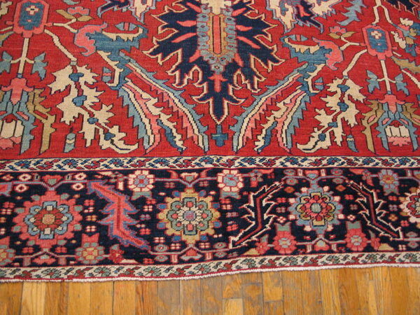A patterned rug in red, navy blue, light blue, and beige rests on natural hardwood floorboards.