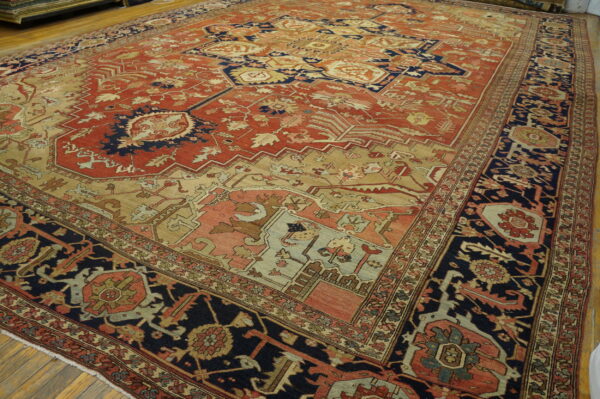 Rust, navy, and tan patterned rug with complex geometric designs covers a light wood floor.