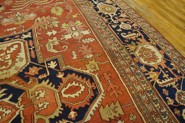 Geometric rug in rust, navy, and tan colors, showing the detailed border on hardwood flooring.