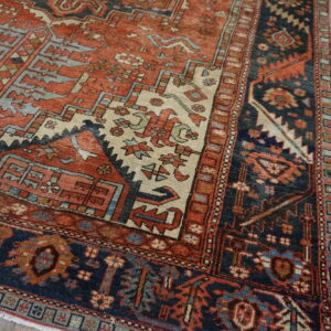 Detailed view of a low-pile rug with geometric patterns in rust, navy, and cream on rustic wood planks.