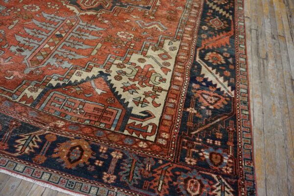 Detailed view of a low-pile rug with geometric patterns in rust, navy, and cream on rustic wood planks.