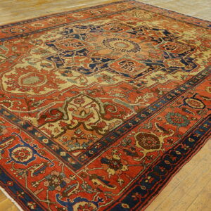 Detailed rust and navy patterned rug featuring a large medallion over light wooden flooring.