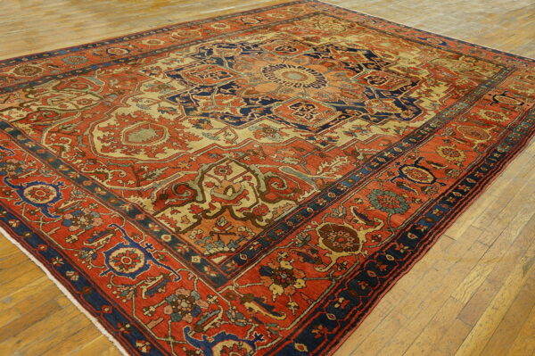 Detailed rust and navy patterned rug featuring a large medallion over light wooden flooring.