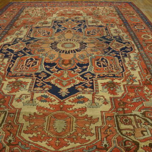 A large medallion rug in coral, cream, and deep blue sits on polished wood flooring.
