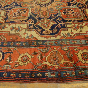 Detailed rug with terracotta, navy, and tan geometric patterns resting on light wood floorboards.