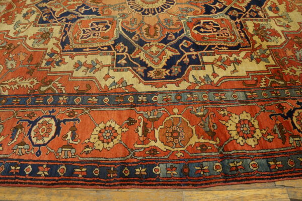 Detailed rug with terracotta, navy, and tan geometric patterns resting on light wood floorboards.