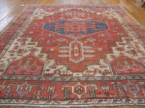 A large geometric rug in shades of red, blue, and cream covers wood plank flooring.
