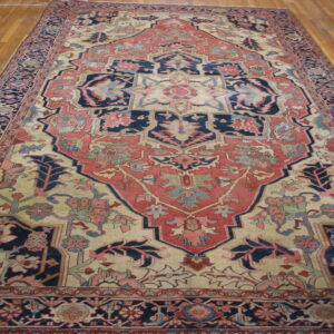 A low pile traditional rug with rust, navy, and beige medallion design on glossy wood floor.