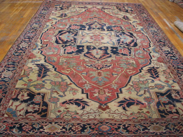 A low pile traditional rug with rust, navy, and beige medallion design on glossy wood floor.