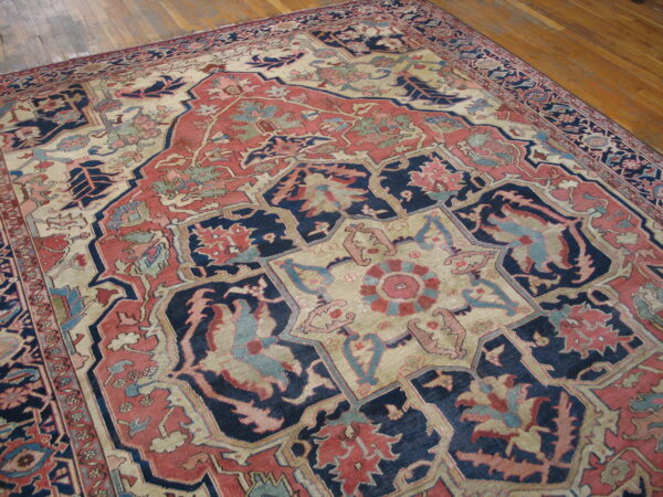 Detailed traditional rug featuring an elaborate medallion pattern in navy, muted red, and cream on wood floors.
