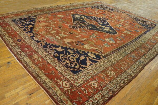 Distressed, low-pile rug featuring a navy medallion on a terracotta field with complex folk motifs on wood flooring.