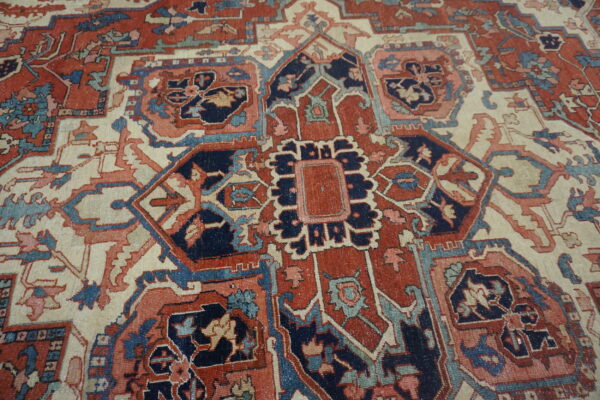 Low-pile rug with geometric and floral motifs in deep red, navy, ivory, and faded teal.