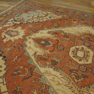 Rust and beige traditional rug with geometric motifs and light blue accents on a wood floor.