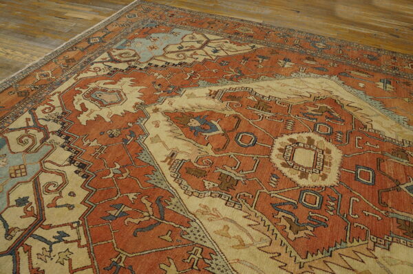 Rust and beige traditional rug with geometric motifs and light blue accents on a wood floor.