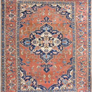 Ornate traditional rug featuring a large navy and cream geometric medallion on a reddish-orange field.